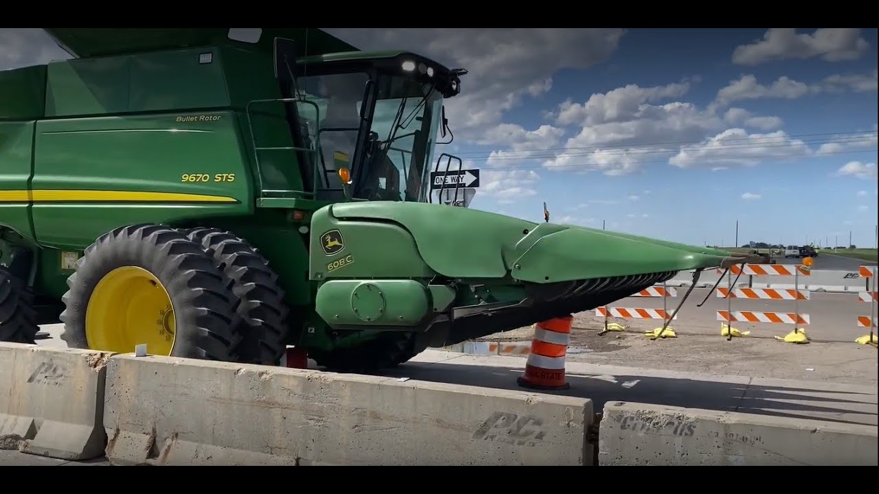 Driver of combine ignores signs, drives over construction barrels