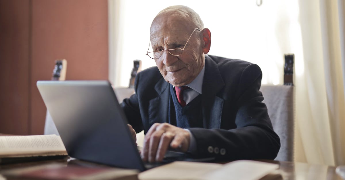 Elderly man in a suit working on a laptop at a desk, representing digital marketing trends and strategies for 2025.