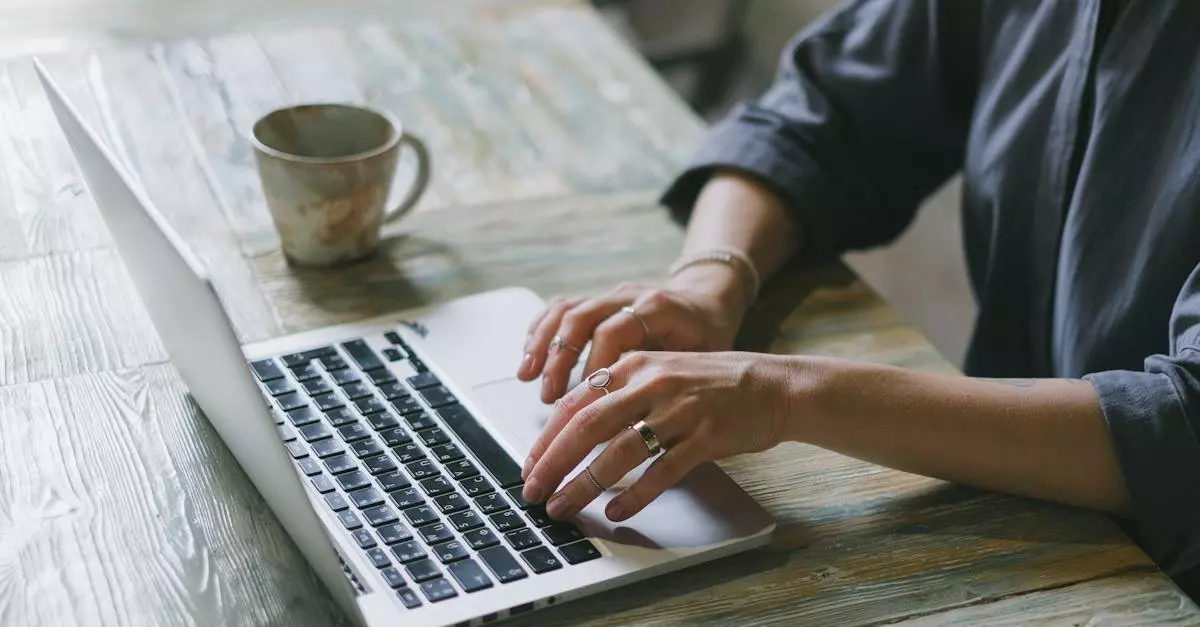Woman Typing On A Laptop At A Wooden Table, Next To A Coffee Mug, Illustrating A Guide On Checking Newly Added Facebook Friends.