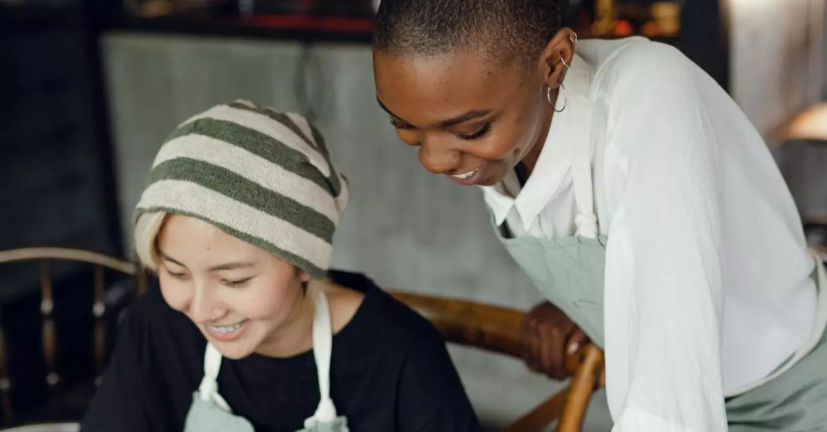 Two Smiling Individuals With Striped Beanie And Aprons Looking At A Computer Screen, Suggesting Collaborative Work Or Online Activities Related To Viewing Ads And Videos.
