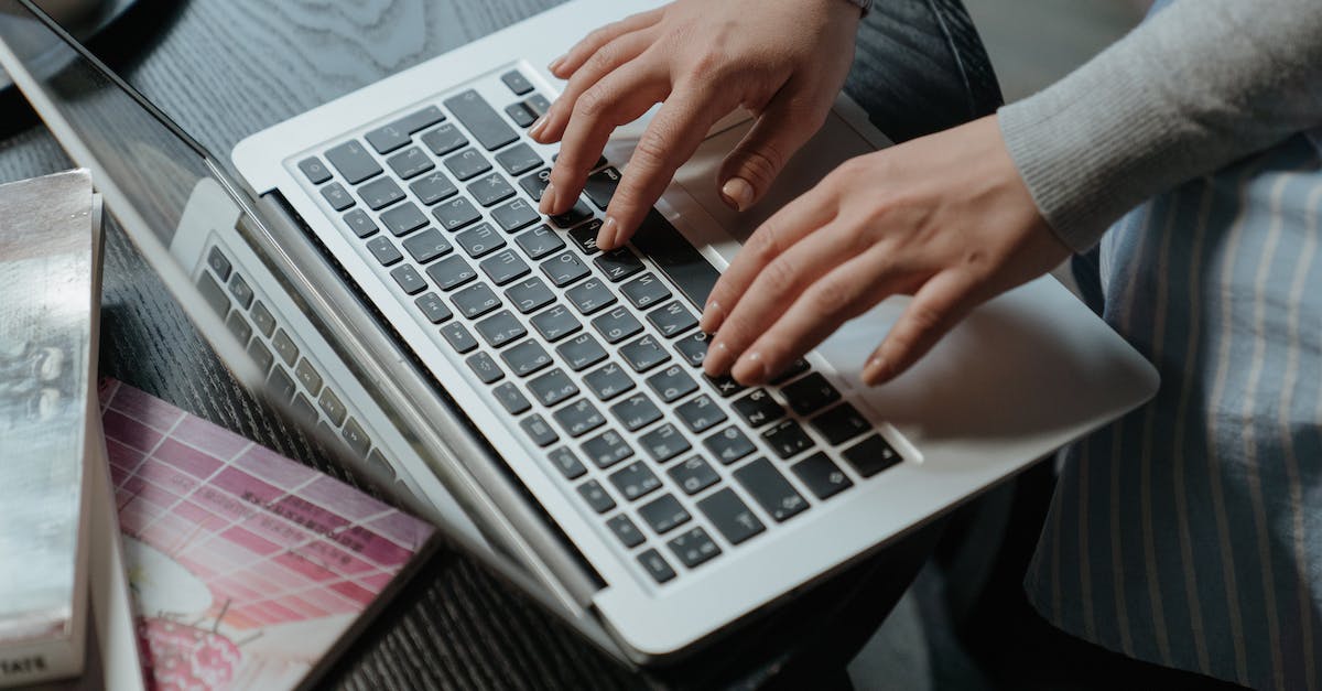 Person typing on a laptop keyboard with digital marketing books nearby, emphasizing 2025 digital marketing trends and maximizing ads and campaign success.
